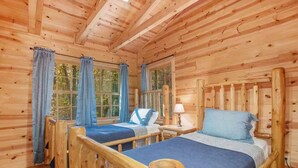 Ein Zimmer in einer Holzhütte mit zwei Betten, großen Fenstern und einer Holzzieldecke.