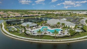 A resort with a central pool, multiple buildings, and a surrounding water body. - Brand New Naples Villa in a Resort Style gated community! (Naples)