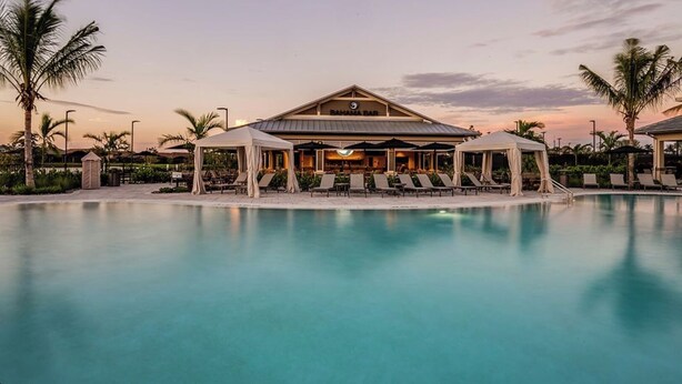 A pool area with lounge chairs and a bar building at sunset. - Brand New Naples Villa in a Resort Style gated community! (Naples)