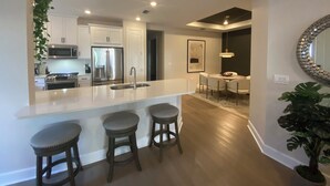 A modern kitchen with white cabinets, stainless steel appliances, and a central island with stools. - Brand New Naples Villa in a Resort Style gated community! (Naples)