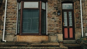 A two-story stone building with a large window and a door with a number plaque. - The Phoenix  (Swansea)