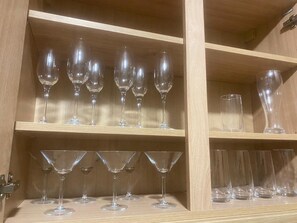 A wooden cabinet with multiple shelves containing various types of clear glassware. - The Phoenix  (Swansea)