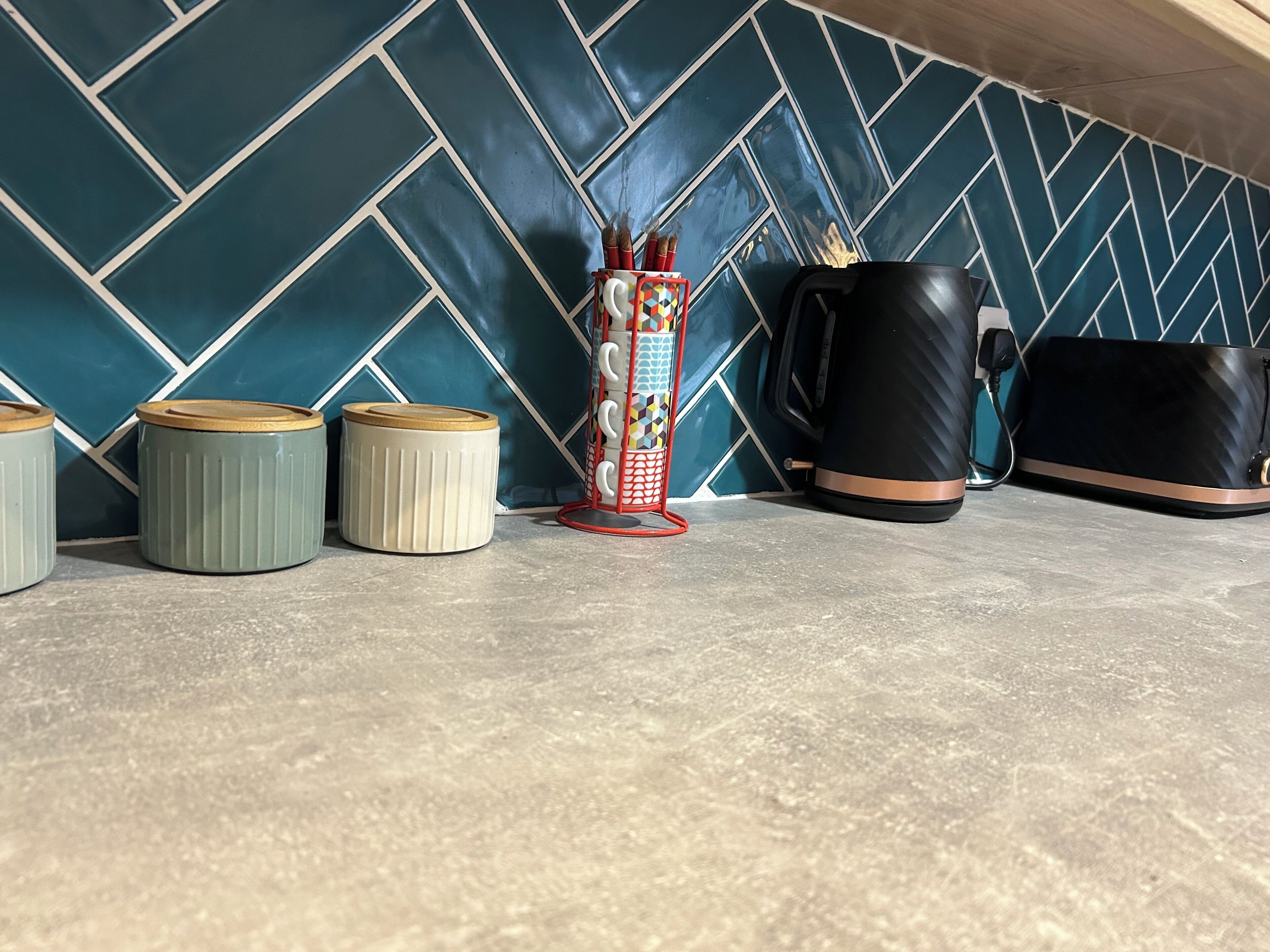Eine Küchenarbeitsplatte mit drei Behältern, einer Tasse und einer Kaffeemaschine.