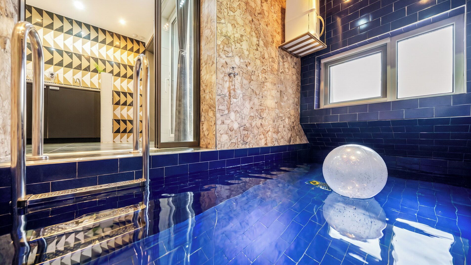 Un bagno moderno con una parete in marmo, un grande specchio e un pavimento piastrellato di blu.