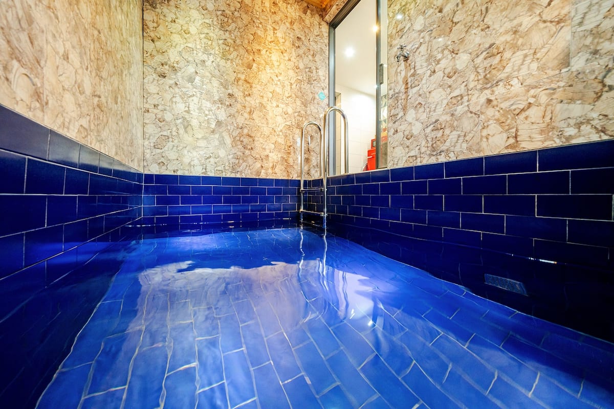 Ein Pool mit blauen Fliesen und einer Steinmauer.