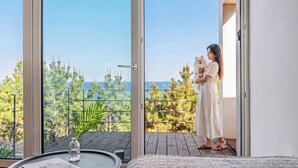 Ein Balkon mit Meerblick, ein Esstisch mit einer Vase und ein Bett.