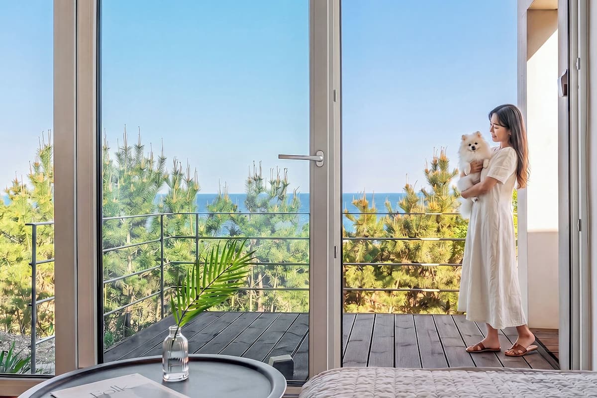 Ein Balkon mit Meerblick, ein Esstisch mit einer Vase und ein Bett.