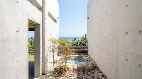 A modern building with a concrete exterior, a small garden with a pond, and a view of the sea. - Yeongdeok Dalto Poolvilla Glamping (Yeongdeok)
