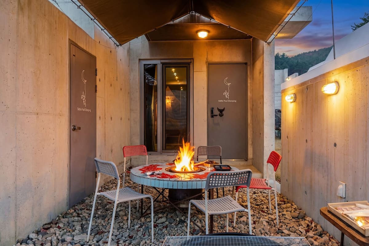 Ein Sitzbereich im Freien mit Feuerstelle, vier Stühlen und einem Tisch.