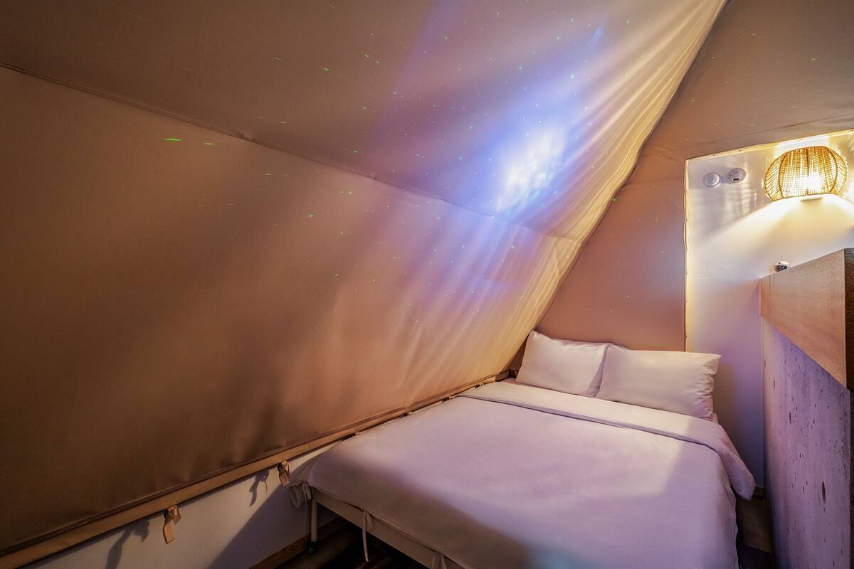 Ein Himmelbett mit einer Lampe an der Wand und einer Decke mit Sterneneffekt.