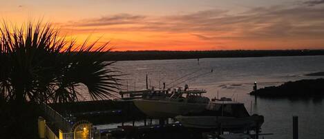 A marina at dusk with boats docked, a walkway, and a view of the water.
