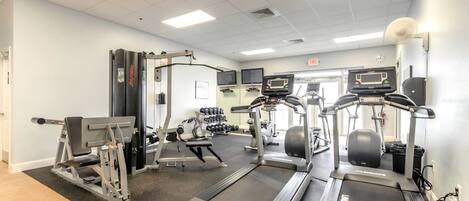 A gym with treadmills, weight machines, and dumbbells.