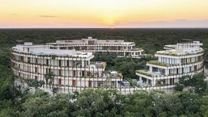 Ein moderner, kreisförmiger Hotelkomplex, umgeben von dichtem Wald, mit mehreren Ebenen und Terrassen.