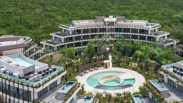A modern hotel with a central pool, surrounded by lush greenery and a clear view of the ocean. - Magnificent studio with pool views, gym and roftop (Tulum)