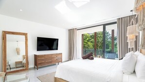 A modern bedroom with a large bed, a TV, a wooden dresser, and a glass table. - Magnificent studio with pool views, gym and roftop (Tulum)