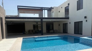 A modern outdoor swimming pool with a clear blue water feature, surrounded by a light-colored deck and a grassy area. - Quinta Ideal for Families: 4 Bedrooms, Swimming Pool, Jacuzzi and Billiards (Portal del Norte)