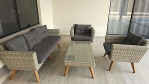 A modern outdoor seating area with wicker furniture and a glass-top coffee table. - Quinta Ideal for Families: 4 Bedrooms, Swimming Pool, Jacuzzi and Billiards (Portal del Norte)