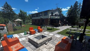 An outdoor patio with stone flooring, orange and blue chairs, and a fire pit. - 5 Bedroom Cottage at Rice Lake! (Alnwick/Haldimand)
