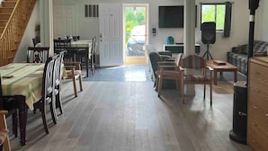 A spacious living area with a dining table, chairs, a sofa, and a television. - 5 Bedroom Cottage at Rice Lake! (Alnwick/Haldimand)