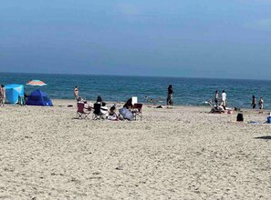 Una playa con tiendas de campaña, sillas y gente.