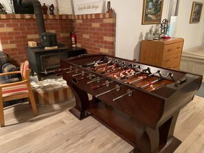 Una mesa de futbolín en una habitación con chimenea de ladrillo, muebles de madera y un armario.