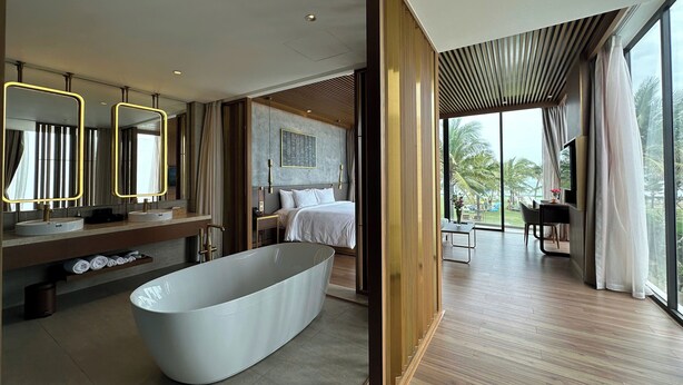 A modern bathroom with a freestanding bathtub, dual sinks, and a large mirror with illuminated edges.