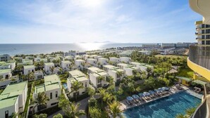 A resort with multiple white buildings, a swimming pool, and a view of the ocean.