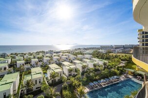 Un resort con varias edificaciones blancas, una piscina y vistas al océano.