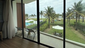 A room with a large sliding glass door leading to a pool area with lounge chairs and umbrellas.