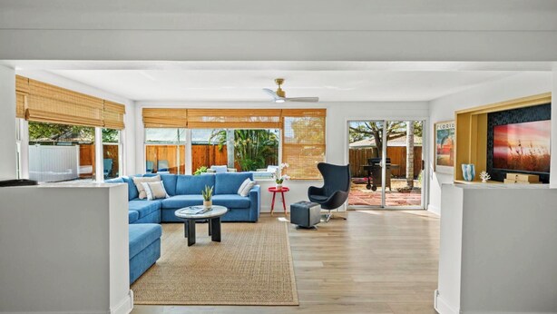 A modern living room with a blue sofa, a coffee table, and a TV on the right. - Coastal Retreat w/ Heated Pool & Games (Largo)