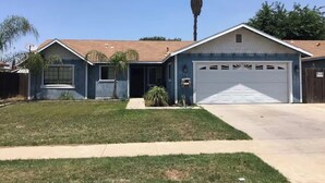 A two-story house with a garage, a front lawn, and a palm tree.