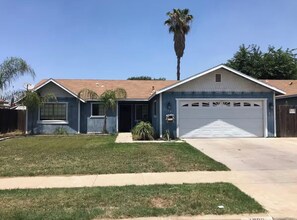 A two-story house with a garage, a front lawn, and a palm tree. - Quiet Cozy Central Valley Home Near Sequoia & Kings Canyon National Parks (Tulare)