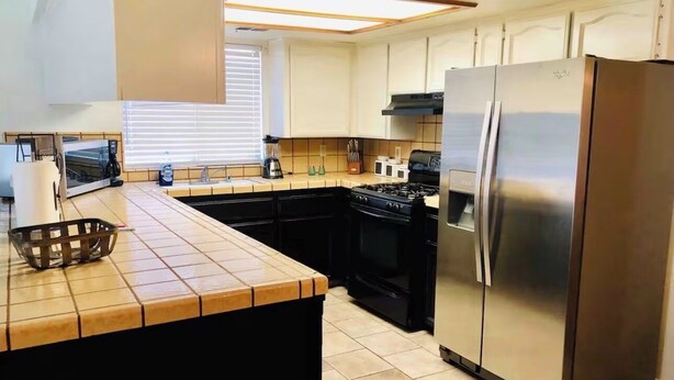 A modern kitchen with a large island, stainless steel appliances, and a tiled backsplash.