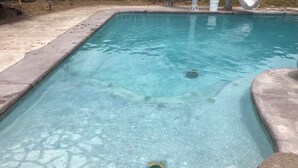 A rectangular swimming pool with clear water, surrounded by a concrete deck.