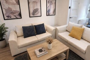 A living room with two beige sofas, a coffee table, and abstract paintings on the wall. - The Cloud House Spa Retreat Hoole (Chester)