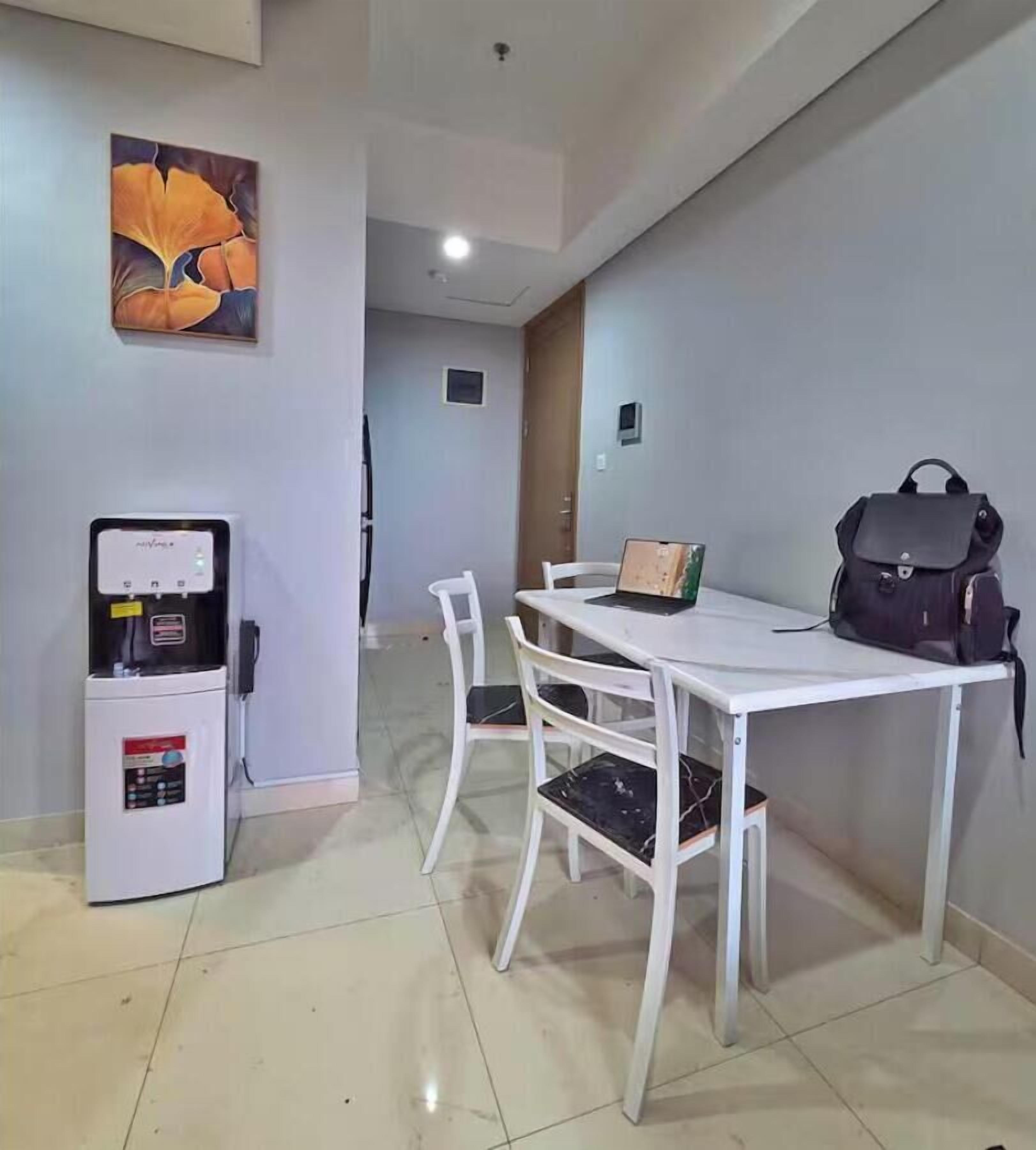 A dining area with a white table and chairs, a water dispenser, and a painting on the wall.