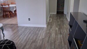 Un couloir avec un plancher en bois, un coin repas avec une table et des chaises, et une bibliothèque.