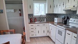 Une cuisine avec des meubles blancs, un four à micro-ondes, une cuisinière et un évier.