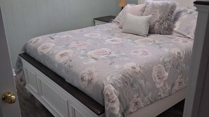 Une chambre à coucher avec un lit, des tables de chevet et une fenêtre avec des rideaux.