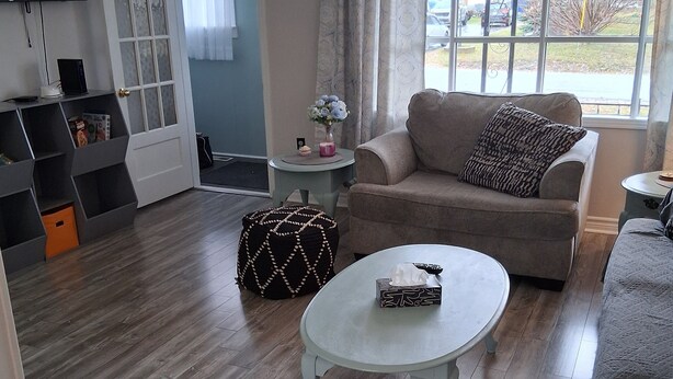 Un salon comprenant un canapé, une table basse, un téléviseur et une porte donnant sur une autre pièce.