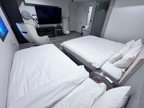 A hotel room with two beds, a desk, a chair, a TV, and a mirror. - MORASTAY (Busan)