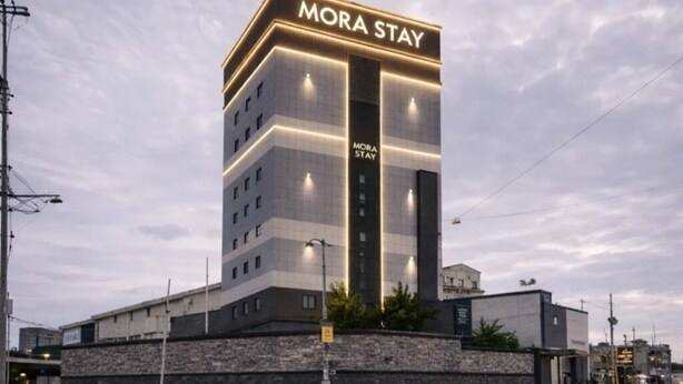 A multi-story hotel named 'MORA STAY' with a prominent sign, a stone facade, and a modern design. - MORASTAY (Busan)