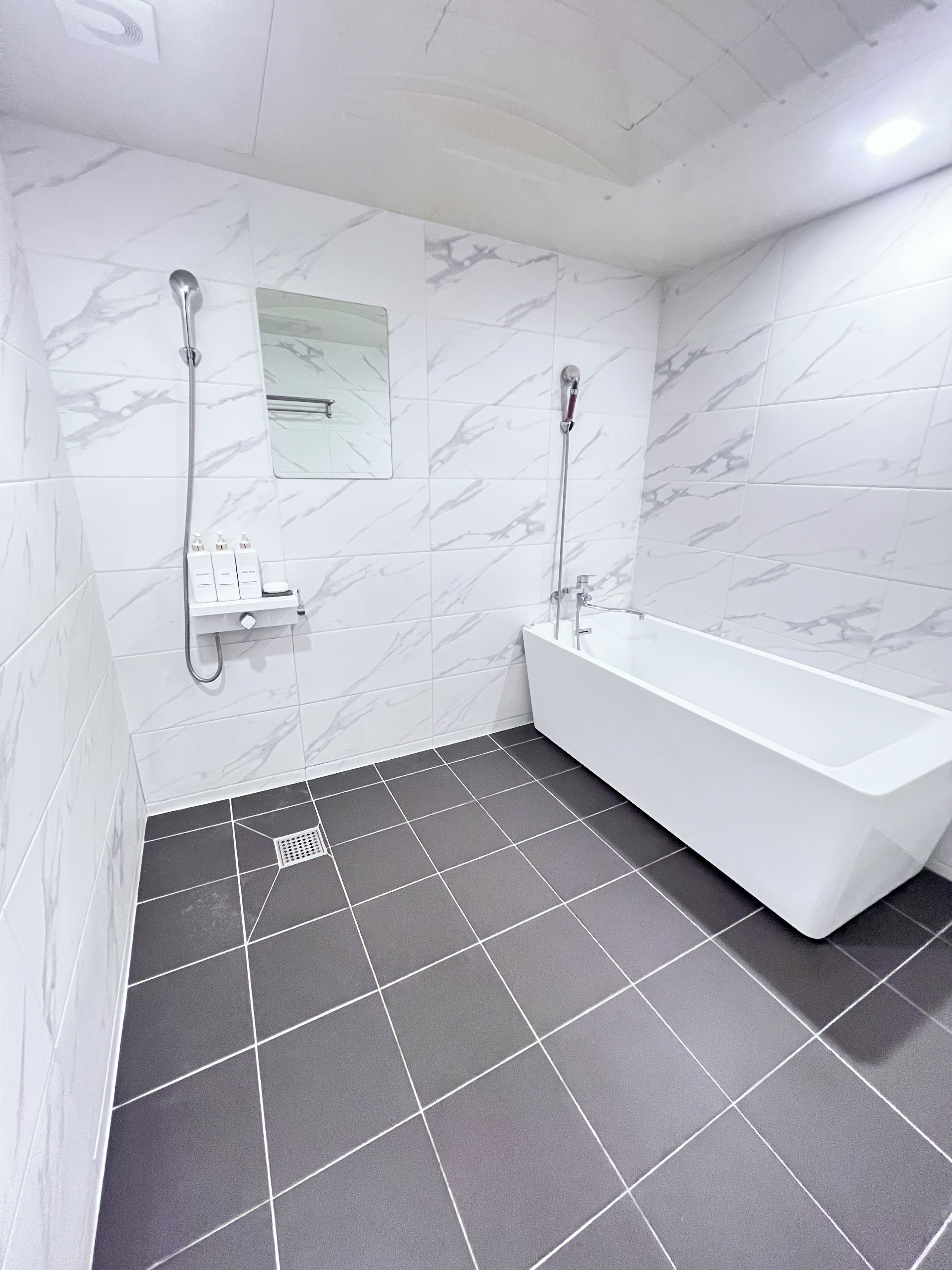 Un baño moderno con una bañera blanca, una ducha y un estante pequeño con artículos de tocador.