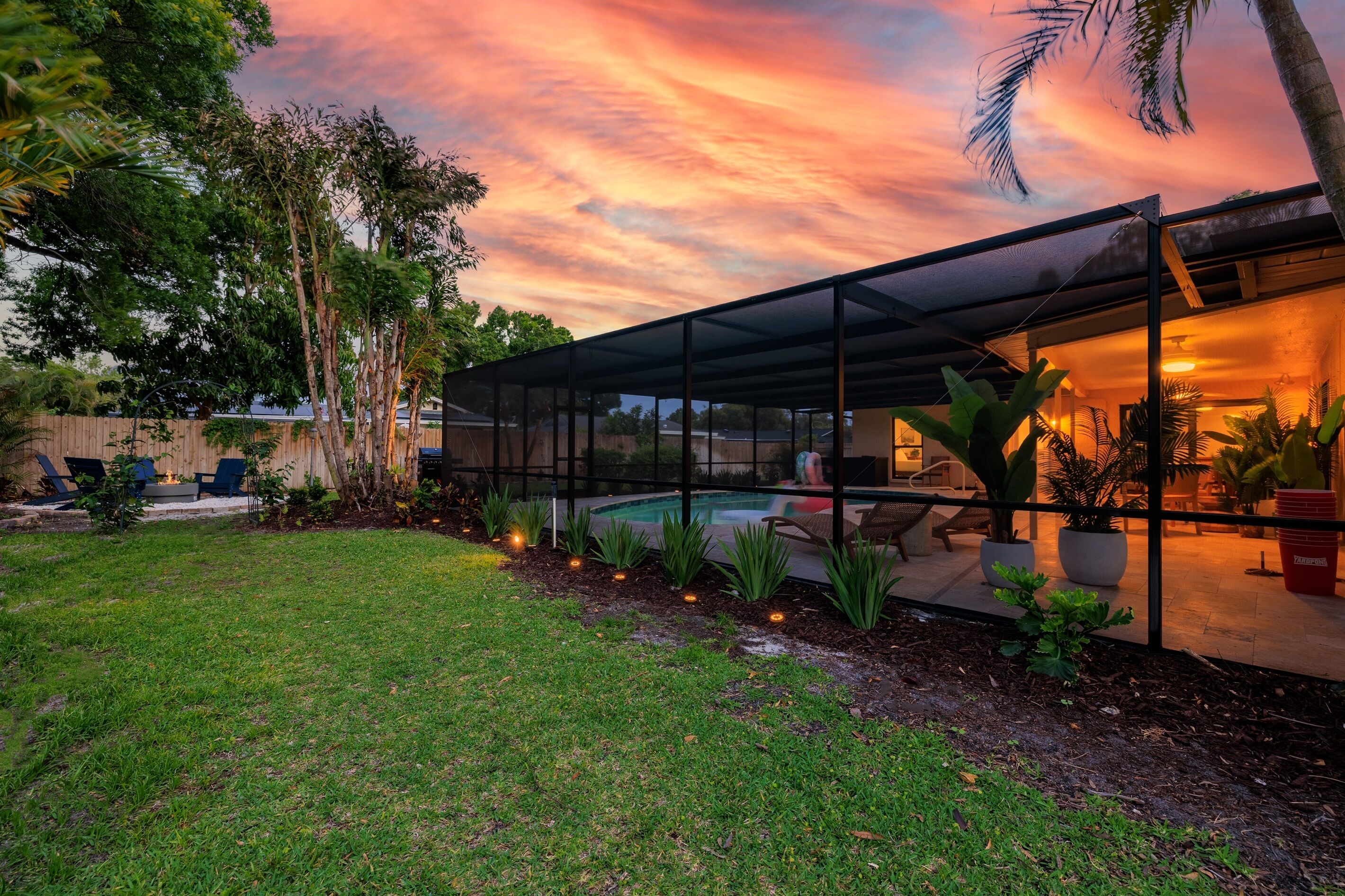 A modern house with a glass-enclosed patio, a swimming pool, and a well-maintained garden.