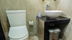 A bathroom with a white toilet, a sink, and a trash bin. - The Crown's Lodge Misty Hideaway  (Nuwara eliya)