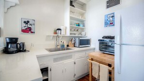 Eine Küche mit weißen Schränken, einer Mikrowelle, einem Toaster und einer Kaffeemaschine.