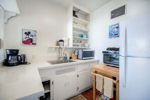 A kitchen with white cabinets, a microwave, a toaster oven, and a coffee maker.