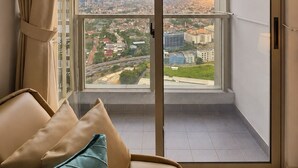 Un balcon avec vue sur la ville, un canapé avec des coussins et un rideau.
