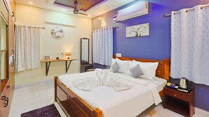 A hotel room with a bed, a nightstand, a mirror, a wall-mounted air conditioner, and a ceiling fan. - Cozy Apartment w/Living room,WIFI,Kitchen,Laundry & Parking in Velachery,Chennai (Chennai)