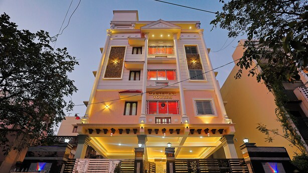 A multi-story hotel with a central entrance, balconies, and decorative lighting. - Cozy Apartment w/Living room,WIFI,Kitchen,Laundry & Parking in Velachery,Chennai (Chennai)